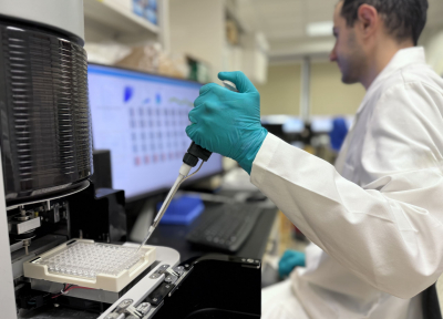 Scientist holding a pipette at a flow cytometry machine