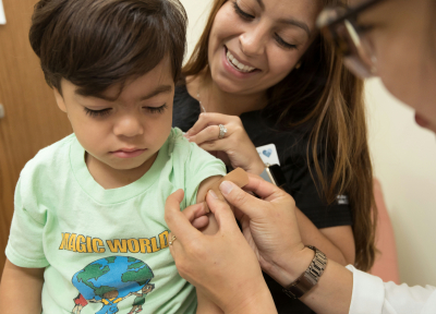 A child in their mother's lap getting a vaccine