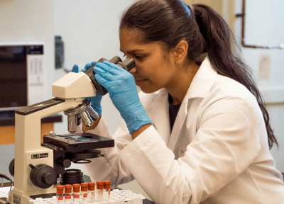 Researcher looking into a microscope